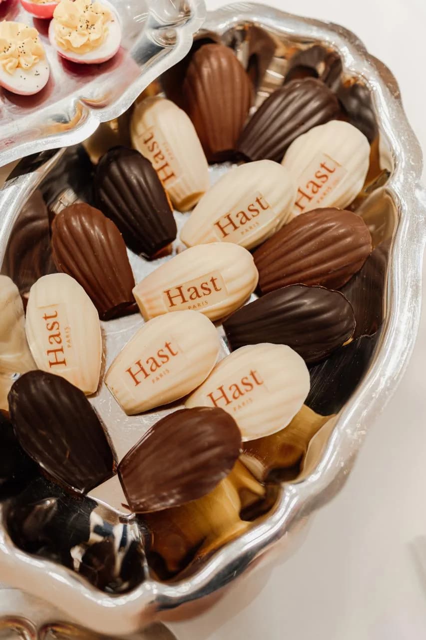 Assortiment de madeleines en chocolat blanc, lait et noir imprimées du logo Hast Paris
